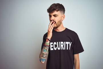 Poster - Young safeguard man with tattoo wering security uniform over isolated white background bored yawning tired covering mouth with hand. Restless and sleepiness.