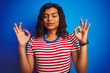 © Krakenimages.com - Transsexual transgender woman wearing stiped t-shirt over isolated blue background relax and smiling with eyes closed doing meditation gesture with fingers. Yoga concept.