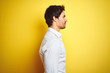 © Krakenimages.com - Young handsome businessman wearing elegant shirt standing over isolated yellow background looking to side, relax profile pose with natural face with confident smile.