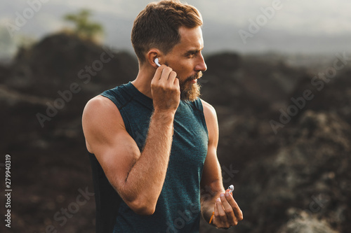 Fotomural Man using wireless earphones air pods on running outdoors