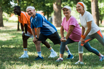 Wall Mural - happy senior and multicultural people exercising on grass