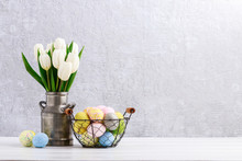 Bouquet Of White Tulips In Silver Can And Wire Basket With Easter Eggs On The Table