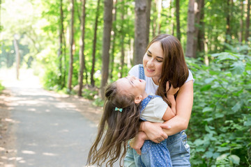 Wall Mural - Family and nature concept - Portrait of mother with her child playing in the green park