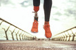 Never give up Cropped photo of disabled woman with prosthetic leg in sportswear jumping on the bridge