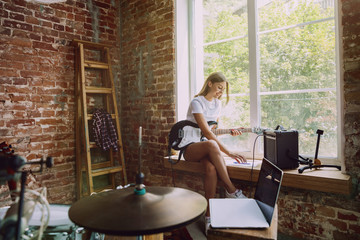 Woman in headphones recording music video blog home lesson, playing guitar or making broadcast internet tutorial while sitting in loft workplace or at home. Concept of hobby, music, art and creation.