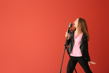 Teenage Girl With Microphone Singing Against Color Background
