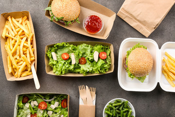 Containers with delicious food on grey background