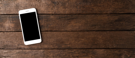 Smartphone with blank screen on wooden table. Banner