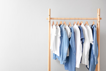 Rack with hanging clothes on light background