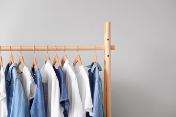 rack with hanging clothes on light background