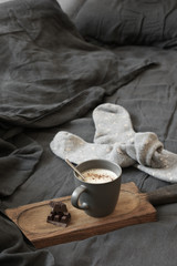 Poster - Coffee latte with chocolate and woolen socks in unmade bed