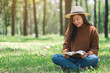 © Farknot Architect - A beautiful Asian woman reading a book while sitting in the park