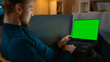 © Gorodenkoff - Man Sitting Relaxes on a Couch Works on a Laptop with Green Chroma Key Screen. Late at Night in His Living Room Man Uses Notebook Computer.