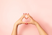 Woman Making Heart With Her Hands On Pink Background