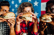 © Тарас Нагирняк - Close up photo. Woman  and man holds burger with hands and fries on the background in cafe. Fresh burger ..