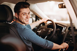 Happy young driver behind the wheel of a car. Buying a car and driving concept.