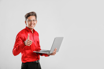 Wall Mural - handsome Indian / Asian male student using laptop and showing thumbs up