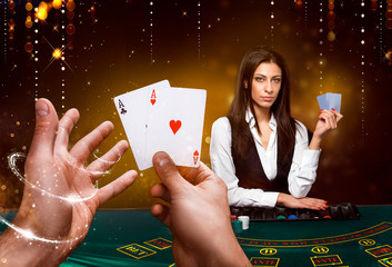 Portrait of a croupier is holding playing cards, gambling chips on table. Black background