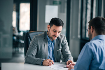 Elegant man signing document, contract with manager.