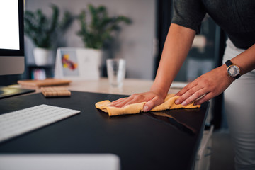 Businesswoman wiping her work desk, close-up.