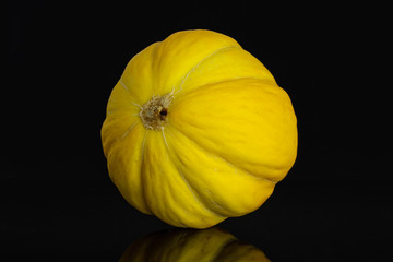 One whole ribbed fresh yellow melon canary isolated on black glass