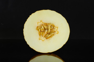 One half of fresh yellow melon canary cross section isolated on black glass