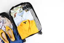 Open Suitcase Fully Packed With Folded Women's Clothing And Accessories On The Floor. Woman Packing For Tropical Vacation Concept. Female Luggage W/ Things. Background, Close Up, Copy Space, Top View.
