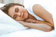© rogerphoto - Beautiful young and happy woman sleeping while lying in bed comfortably and blissfully smiling