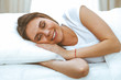 © rogerphoto - Beautiful young and happy woman sleeping while lying in bed comfortably and blissfully smiling