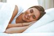© rogerphoto - Beautiful young and happy woman sleeping while lying in bed comfortably and blissfully smiling
