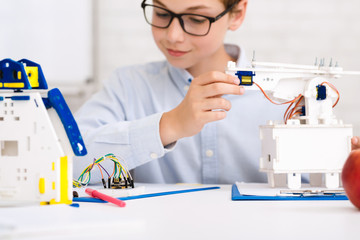 Poster - Concentrated boy constructing robot at class, closeup