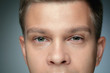 Close-up portrait of young man isolated on grey studio background. Caucasian male model looking at camera and posing, looks serious. Concept of men's health and beauty, self-care, body and skin care.