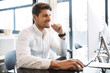 © Drobot Dean - Image of happy businesslike man sitting at table and working on computer in office