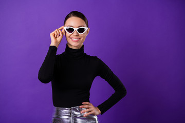 Portrait of charming glad person touching her specs smiling at camera wearing black turtleneck isolated over purple violet background