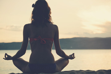 Young woman practicing yoga on the sandy beach.