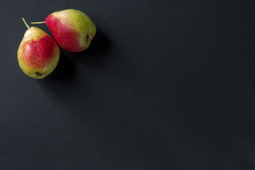 two ripe pears on a dark grey background