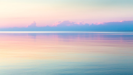 Morning clear seascape with colorful sky. Natural soft background. Beautiful magical pink and gold reflected in the water.