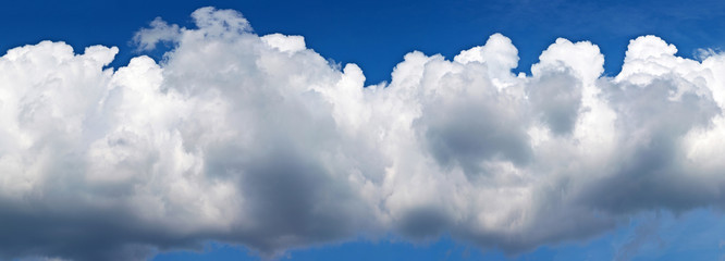 Wall Mural - panoramic view of a beautiful cumulus cloud against a blue sky in a sunny summer day. natural cloudy
