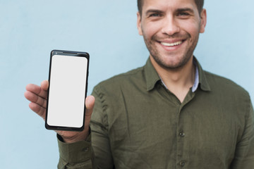 Smiling stubble young man holding white blank screen smartphone