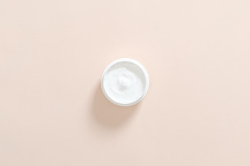 Jar with moisturizing hand cream on pastel pink background. Skin care cosmetic concept. Minimal flat lay style composition, top view, overhead.