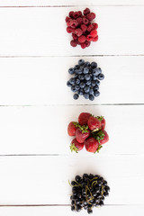 Wall Mural - raspberries, blueberries, strawberries, fresh summer berries lie on a white table in heaps