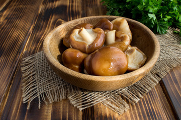 Marinated mushrooms shiitake in the brown plate on the  rustic wooden background