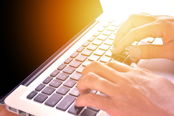 Close-up of typing male hands on keyboard with sunlight