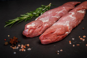 two long pieces of raw marbled meat with green rosemary