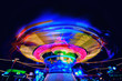 © stefanholm - Bright colorful carosuell in neon colors in motion at a fun fair during evening.