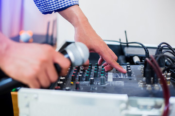 Microphone in hand and adjust an audio mixer controller in the control room, Sound mixer control for live music and studio equipment, Quality audio system for professionals,