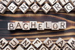 bachelor - word from wooden blocks with letters, *** concept, random letters around, top view on wooden background