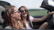 © ASDF - two fashionable girls travel in a convertible car.