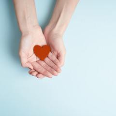 Wall Mural - a person holding red heart in hands, donate and family insurance concept, on aquamarine background, copy space top view