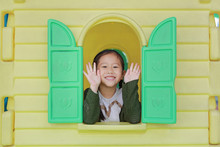 Happy Little Asian Child Girl Playing With Window Toy Playhouse In Playground.